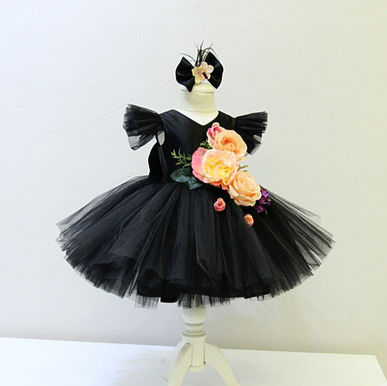 Black tulle tutu dress with big floral bouquet and big bow on the back.  Matching headpiece included.  Short plunging neck line.